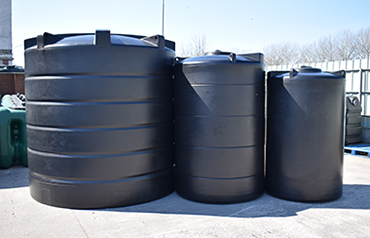 Drie zwarte bovengrondse kunststof regenwatertanks in verschillende formaten voor wateropslag en hergebruik.