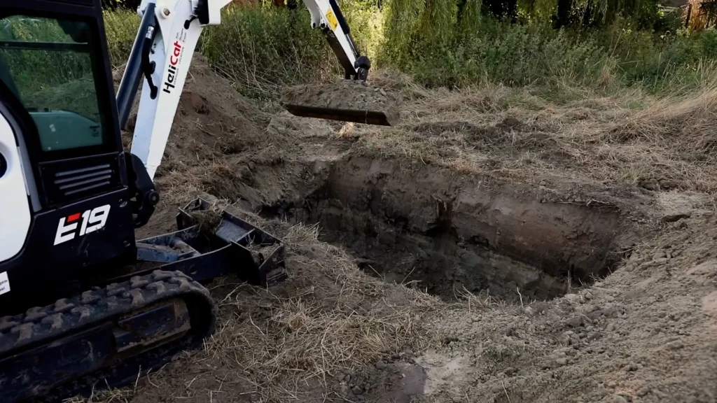 Stappenplan regenwaterput plaatsen. Minigraver graaft een kuil voor de plaatsing van een ondergrondse regenwaterput.