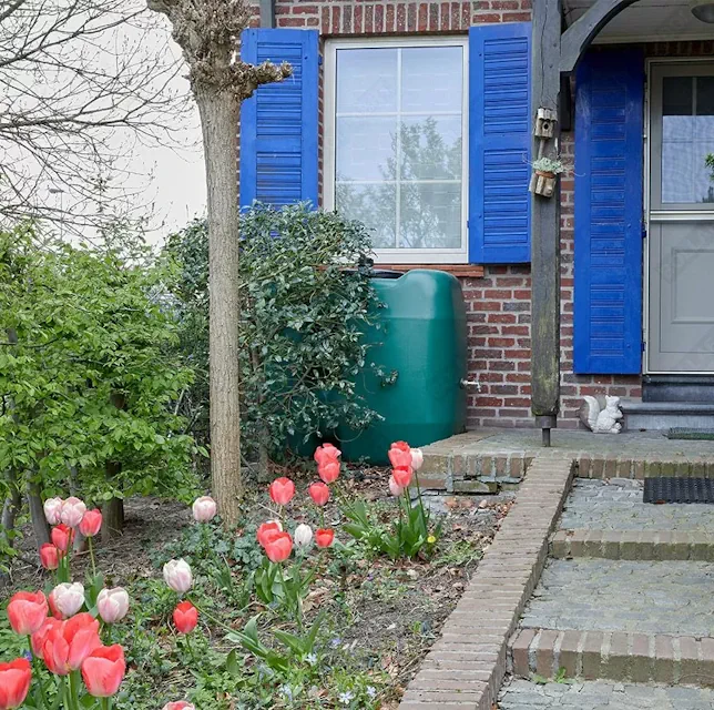 Bovengrondse regenwatertank voor het opvangen van regenwater in een voortuin.
