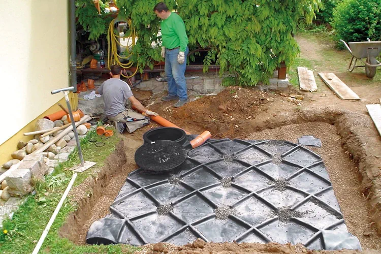Plaatsing van een ingegraven regenwaterput met leidingen, als voorbeeld voor het bepalen van de juiste regenwaterput grootte.